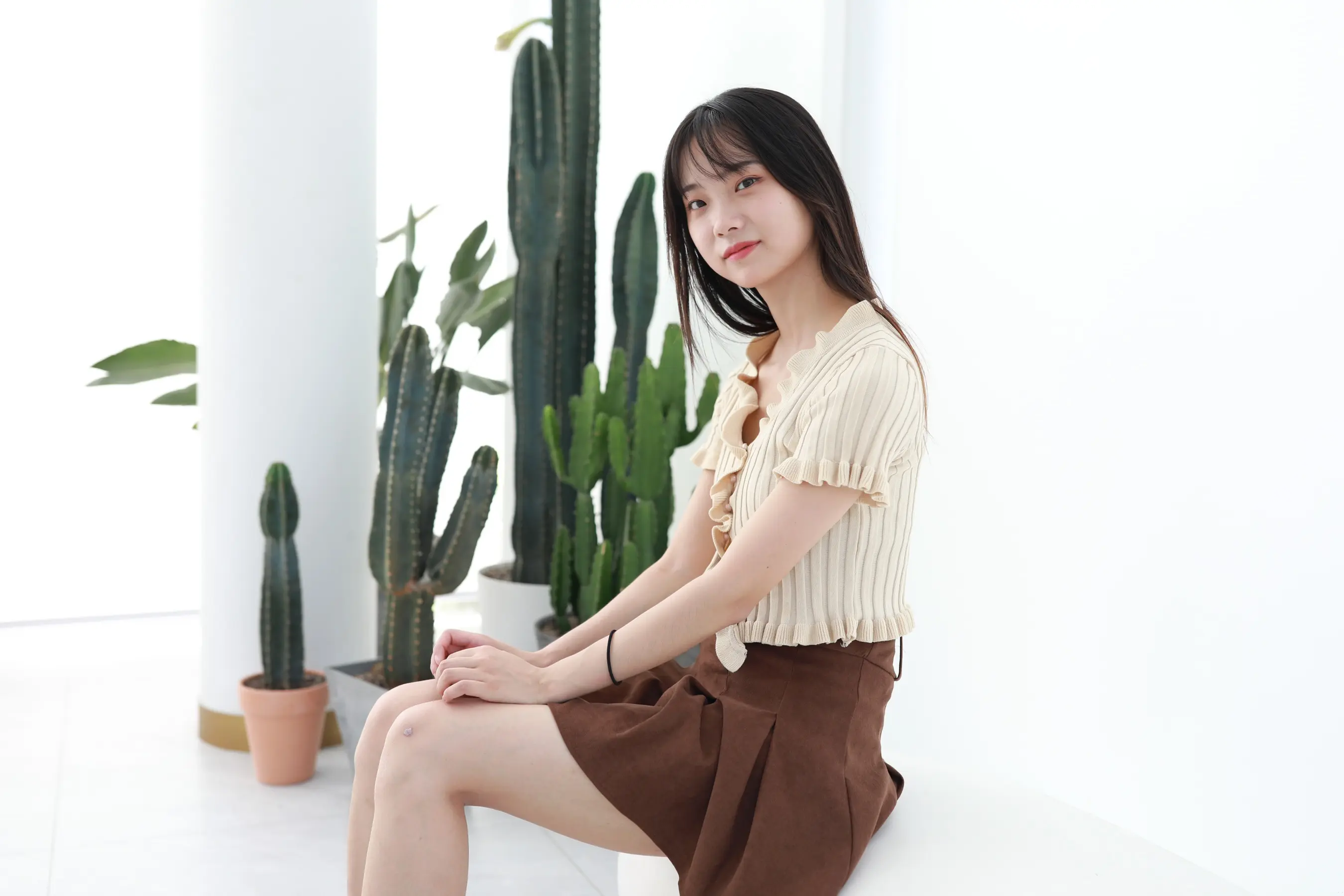 坐在仙人掌旁边的白色长凳上的 arafed 女人