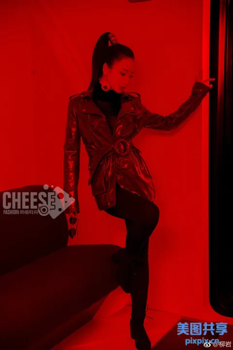 在红色房间里，穿着皮夹克的女人靠在墙上