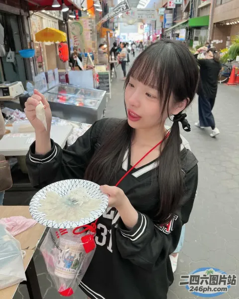 女子在拥挤的街道上拿着一盘食物，路过的人们