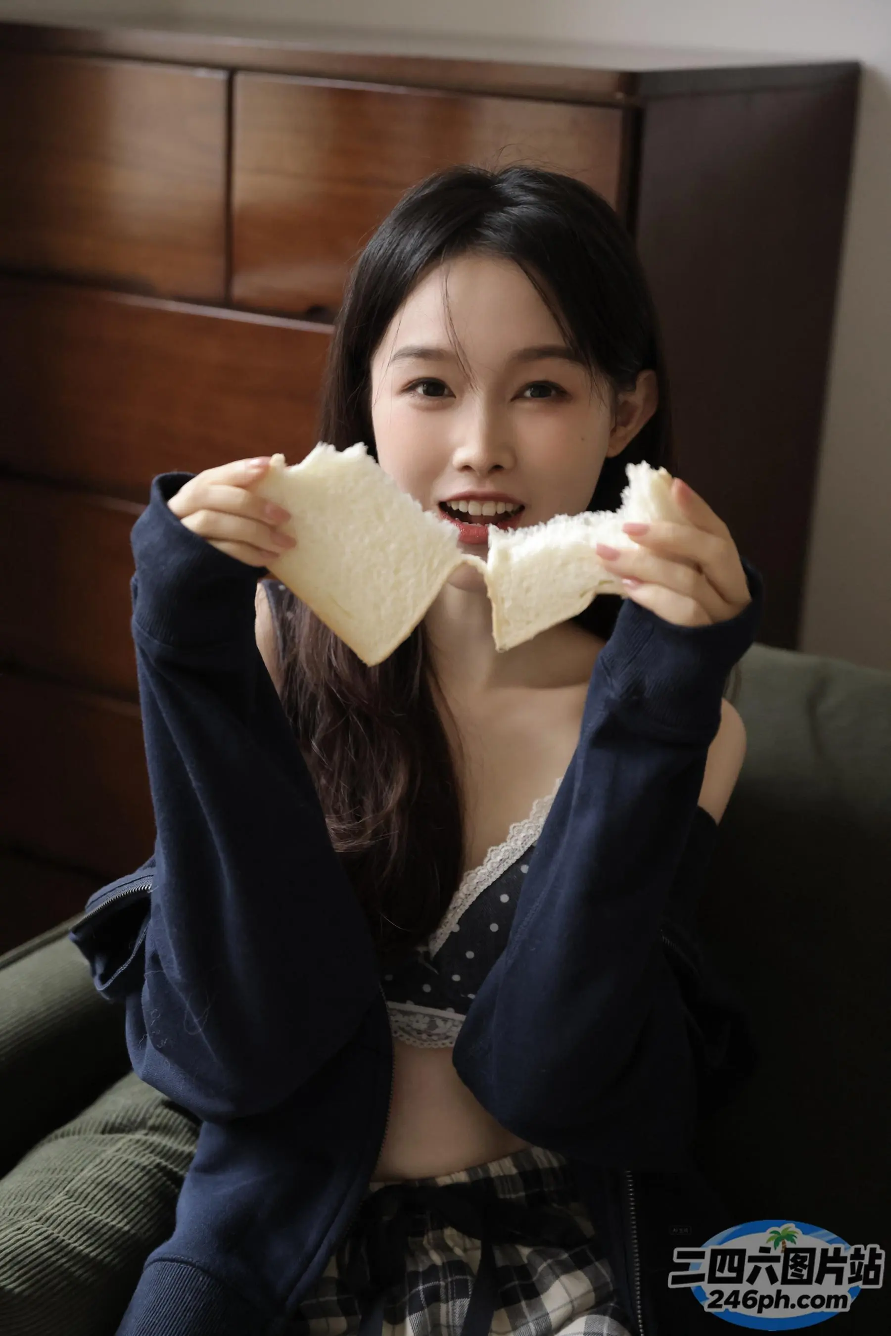 坐在沙发上吃面包的 Araffed 亚洲女人