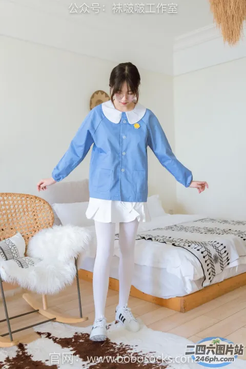 穿着蓝色衬衫和白色裙子的阿拉夫德女人站在床上
