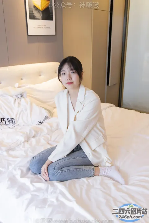 穿着白衬衫和牛仔裤坐在床上的阿拉菲德女人