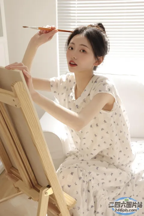 白衣女子用画笔在画架上绘画