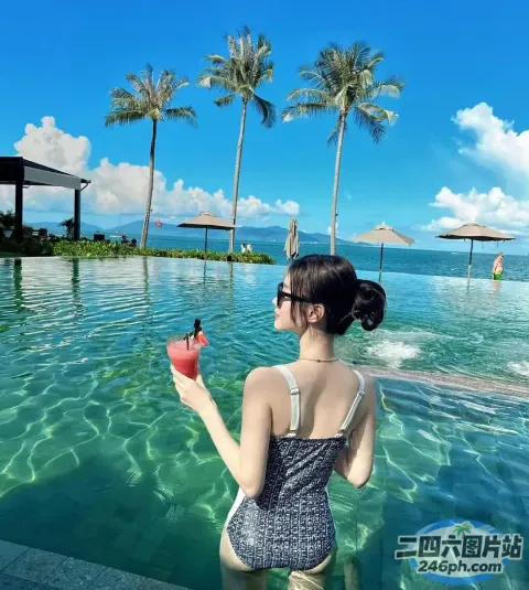 穿着泳衣的女人在游泳池里拿着饮料