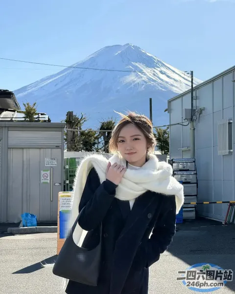 一个女人站在山前，手里拿着一个黑色的包