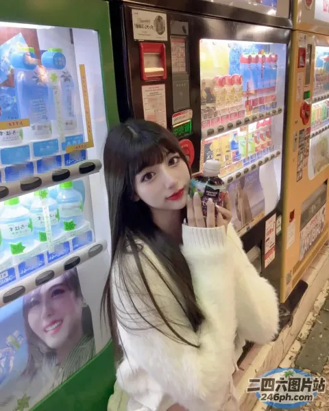 身穿白色毛衣的女子在自动售货机前拿着手机