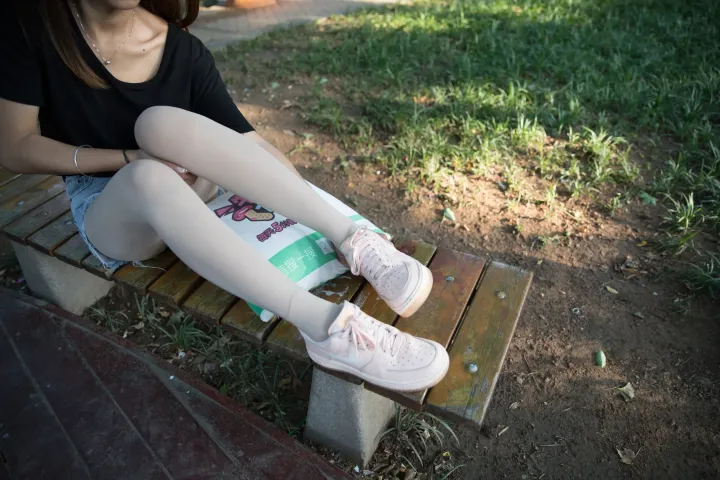 有个女人坐在长凳上，双腿交叉