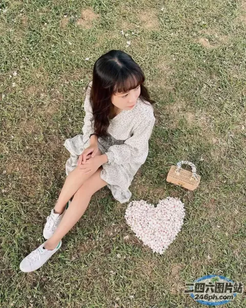 阿拉菲女孩坐在草地上，手里拿着一个心形物体