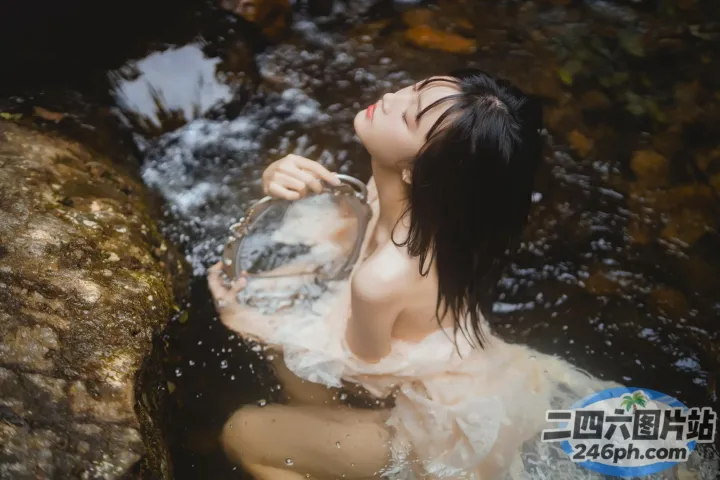 溪流中坐着一个穿着白色连衣裙的女人