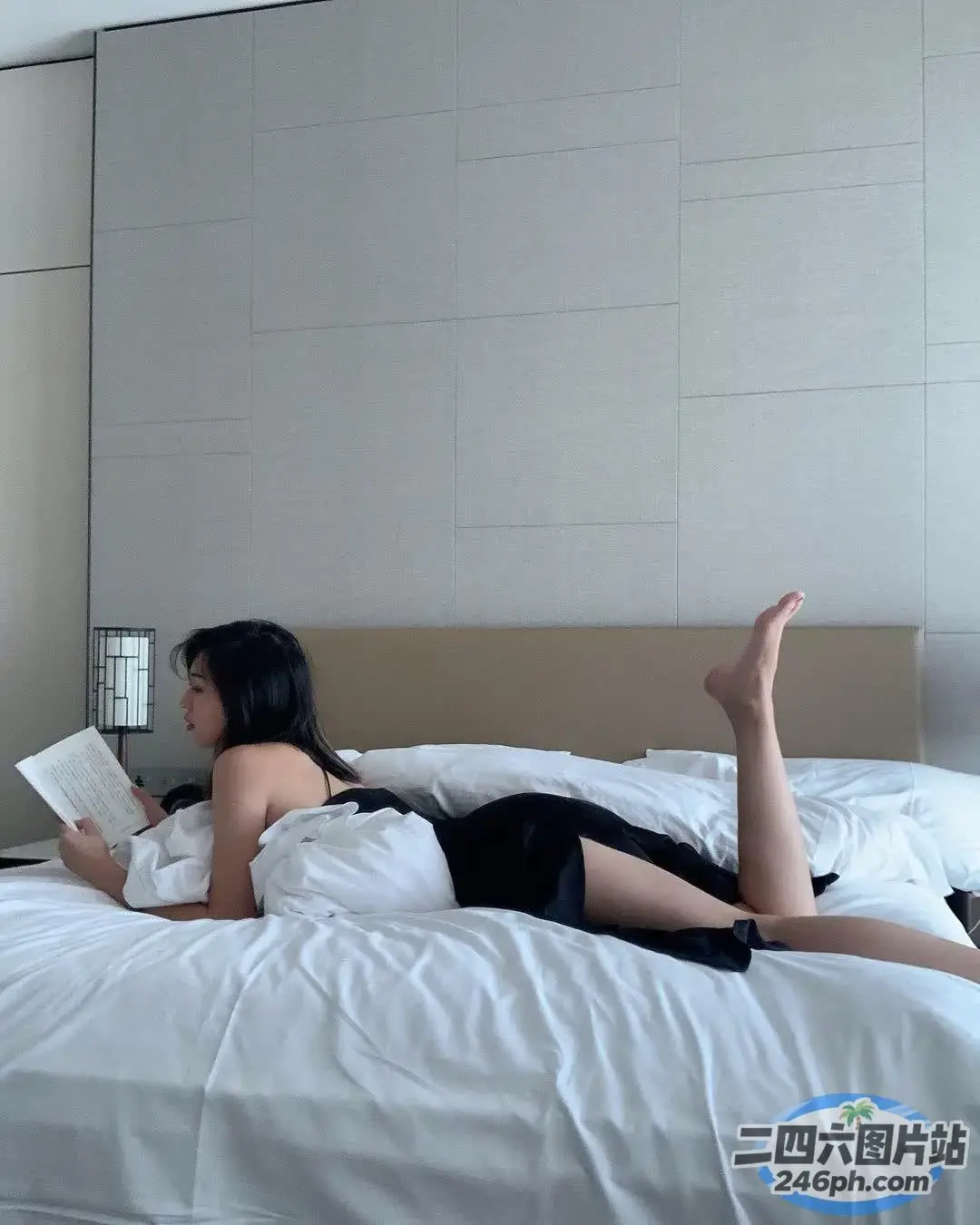 女子穿着黑色连衣裙躺在床上看书
