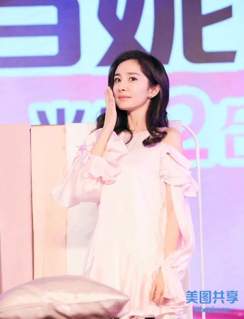 身穿粉色连衣裙的阿拉菲女人拿着麦克风站在舞台上
