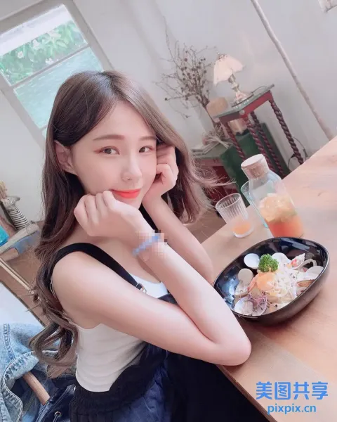 一位女士手里拿着一碗食物坐在桌子旁