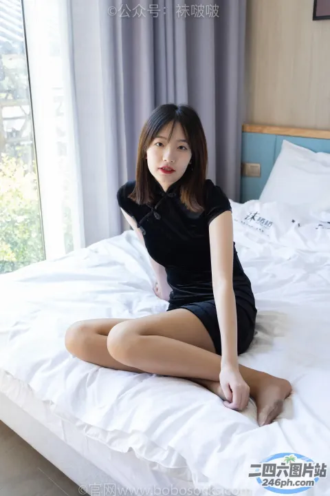 穿着黑色连衣裙坐在床上的 arafed 亚洲女性