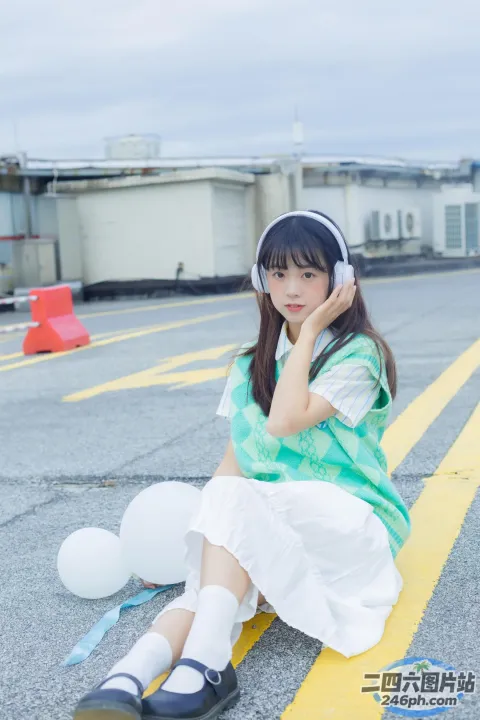 地上坐着一个年轻女孩，手里拿着气球
