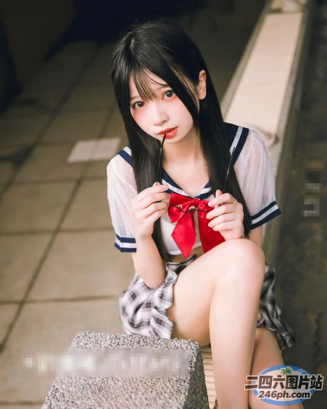 有一个女人坐在壁架上，手里拿着红色的蝴蝶结
