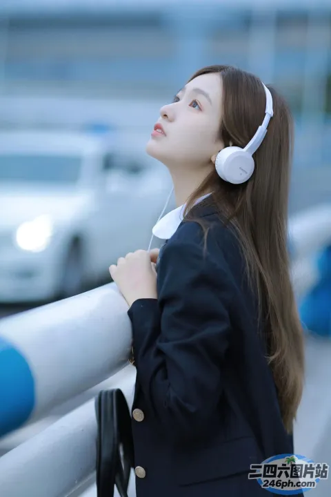 戴着耳机靠在栏杆上看汽车的女人