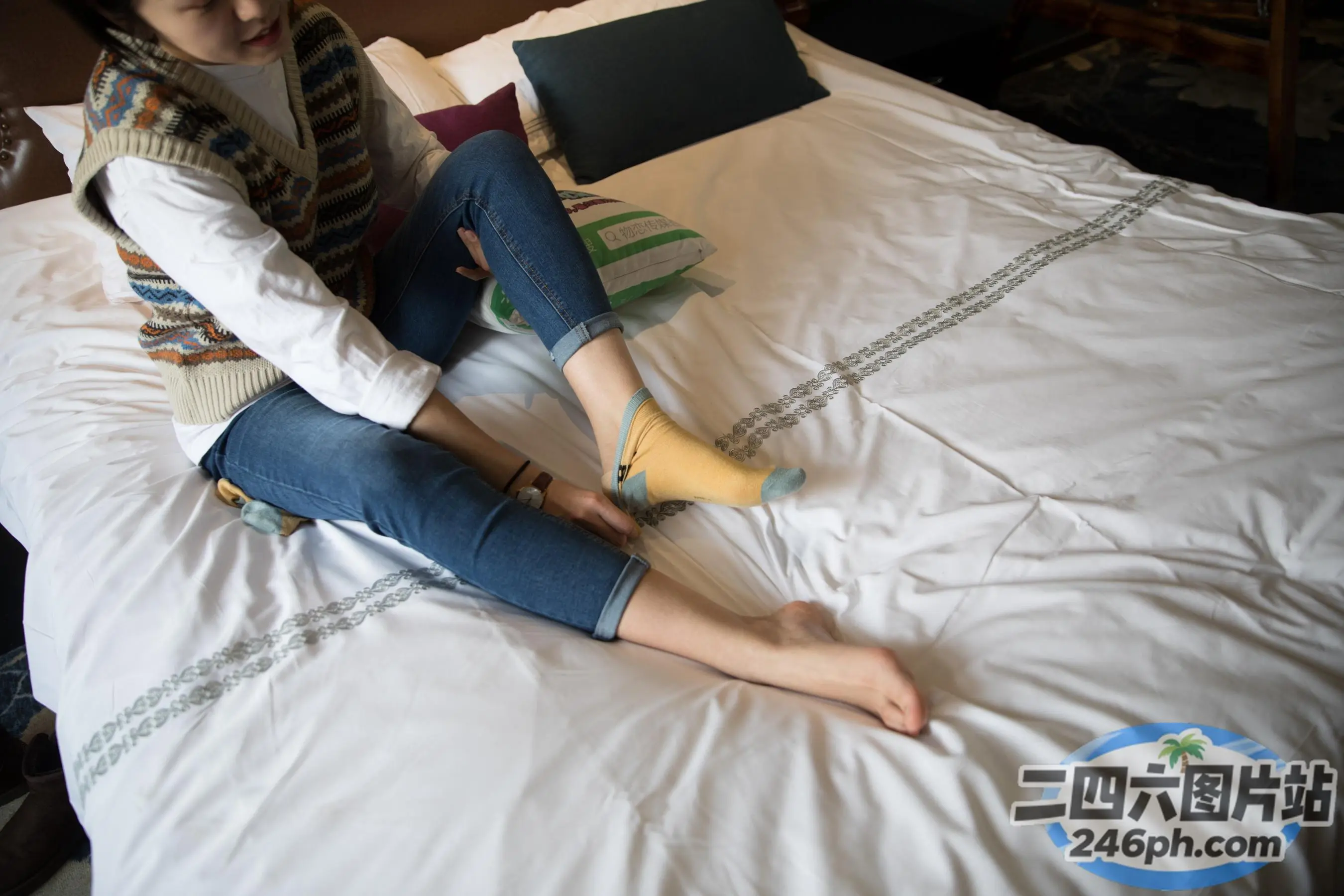 女人坐在床上，拿着笔记本电脑和袜子