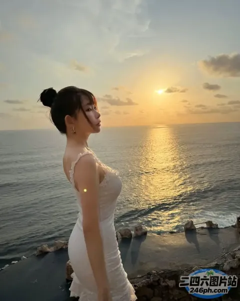 一个身穿白色连衣裙的女人站在俯瞰大海的悬崖上