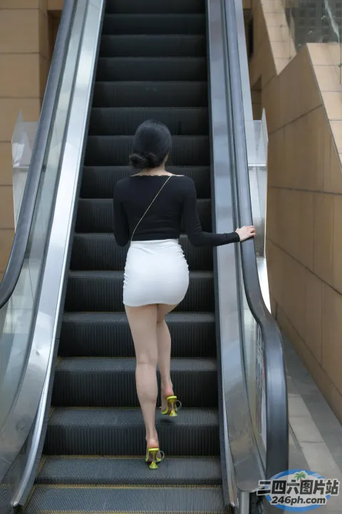 穿着裙子的 Araffe 女子乘坐自动扶梯从楼梯上下来