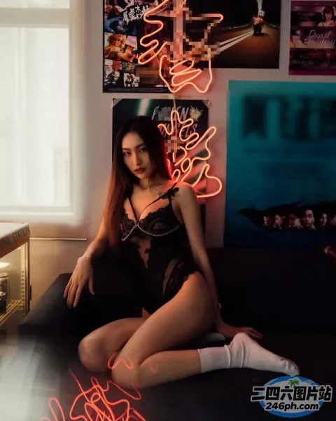 有一个女人坐在一个房间里的沙发上，房间里挂着霓虹灯