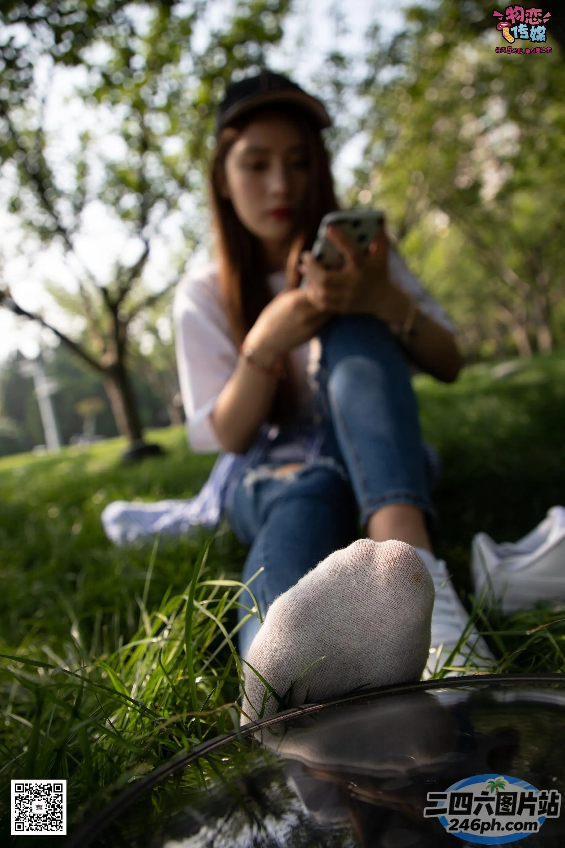 阿拉菲坐在草地上，手里拿着手机