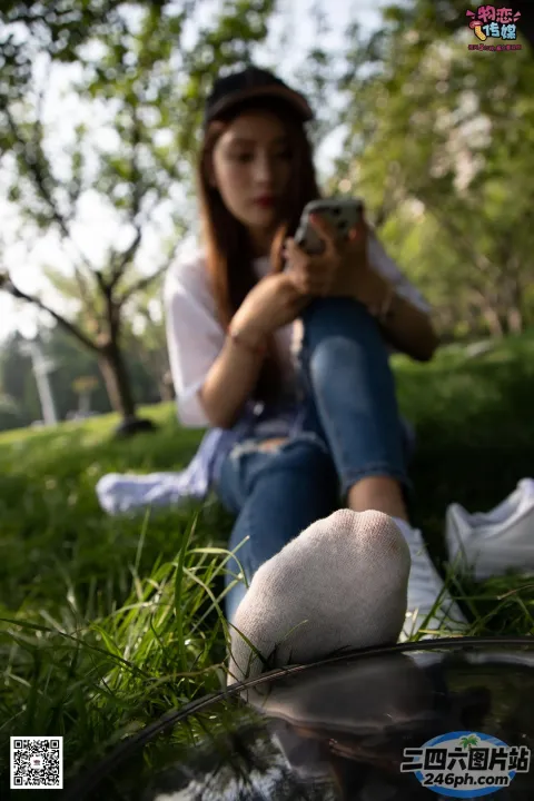阿拉菲坐在草地上，手里拿着手机