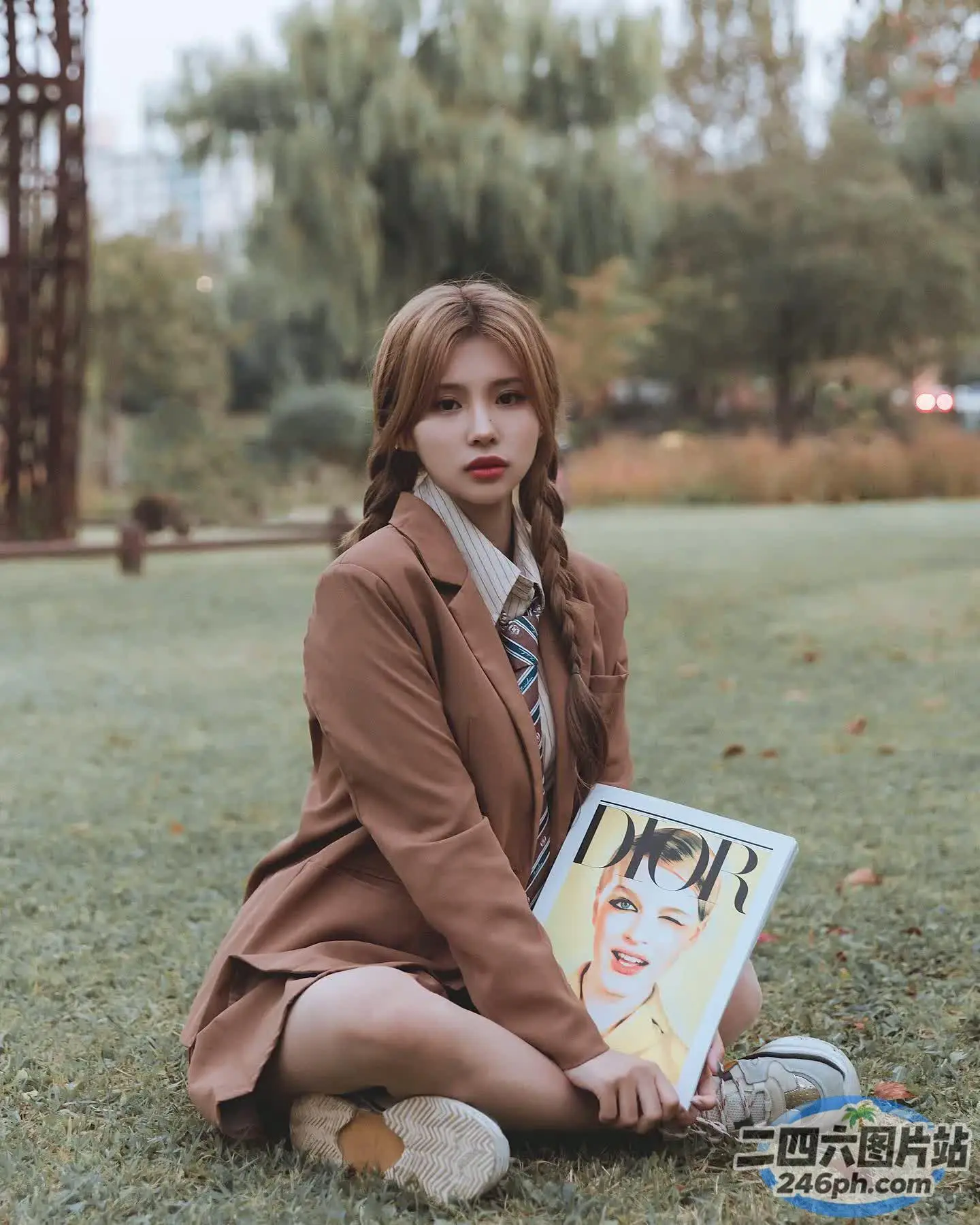 拿着杂志和相机坐在草地上的 arafed 女人