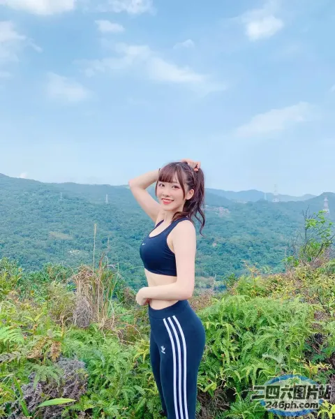 一个穿着运动文胸上衣和紧身裤的女人站在山上