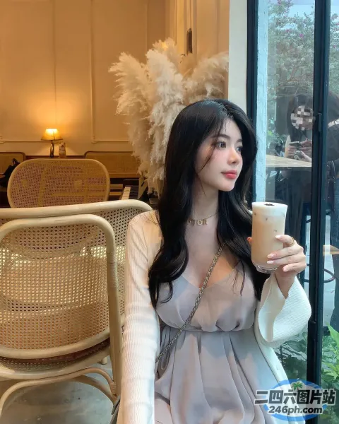 有个女人坐在桌子旁，手里拿着一杯咖啡