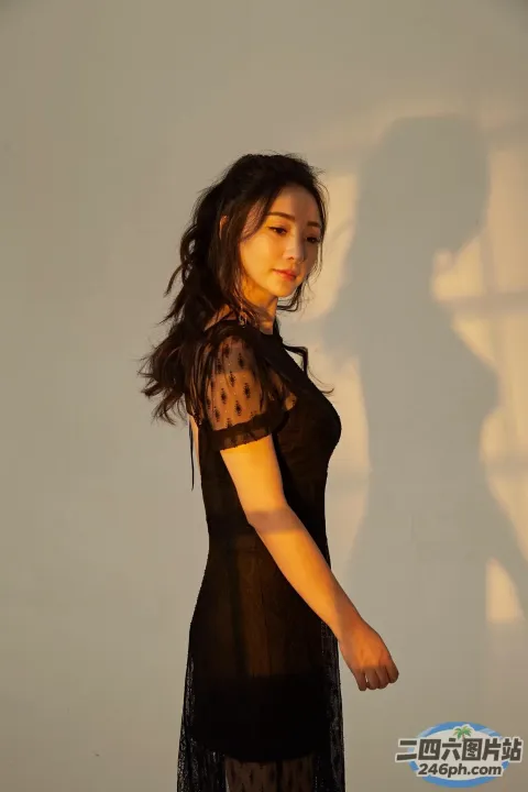身穿黑色连衣裙的阿拉夫德女子站在白墙前
