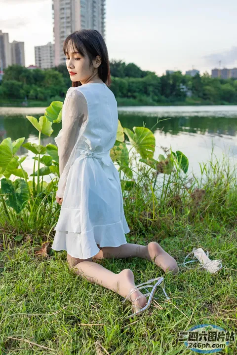 一名妇女坐在水体附近的草地上