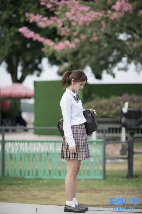 人行道上站着一个女人，手里拿着一个袋子