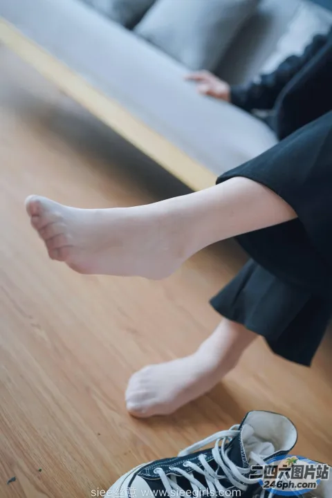 有人坐在沙发上，脚抬起来，穿着一双运动鞋