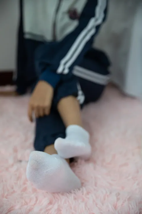 有一个人坐在粉红色的毯子上，穿着白色的袜子