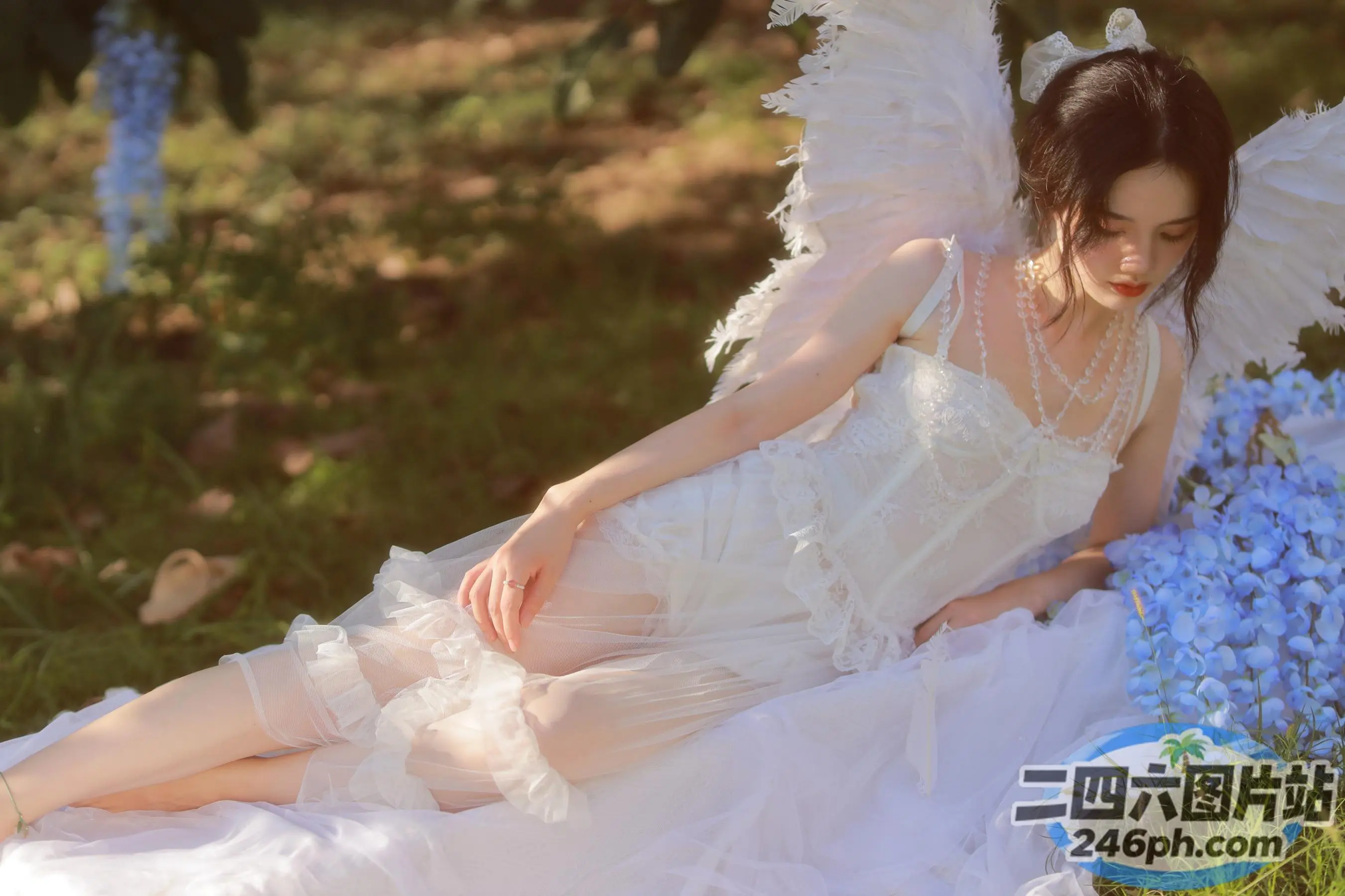 有一个穿着白色连衣裙的女人坐在花坛上