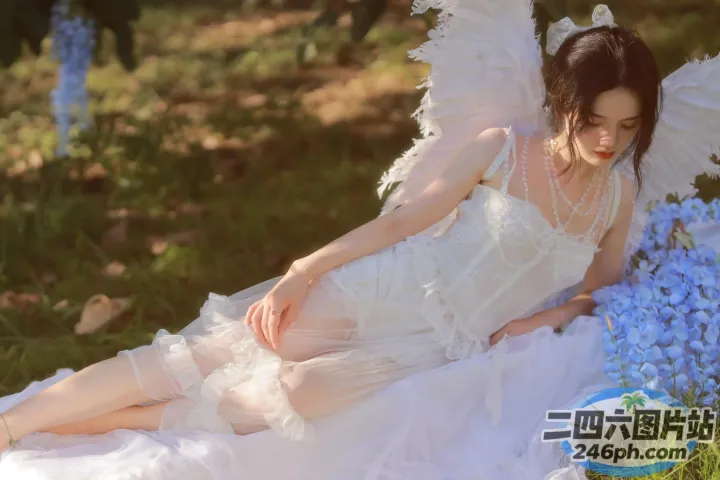有一个穿着白色连衣裙的女人坐在花坛上