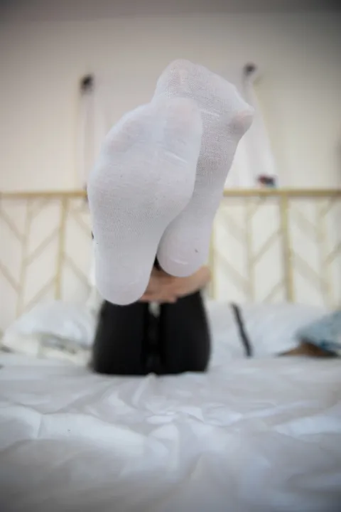 有人坐在床上，双脚抬起