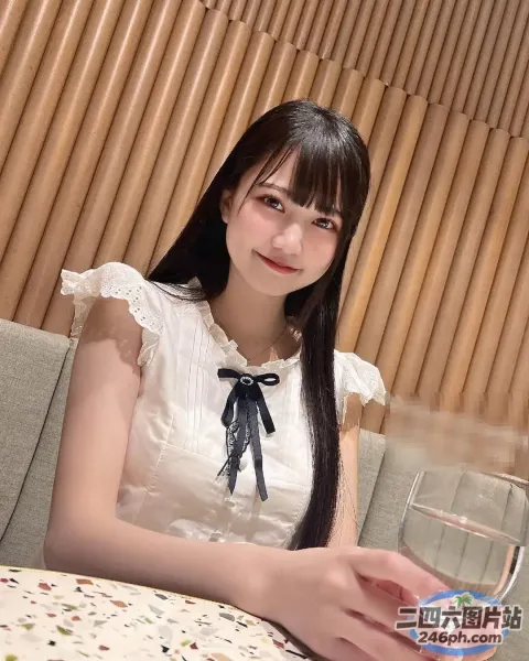 有个女人坐在桌子旁，手里拿着一杯水