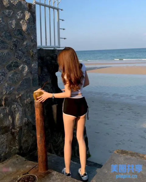 海边的石墙上站着一个女人