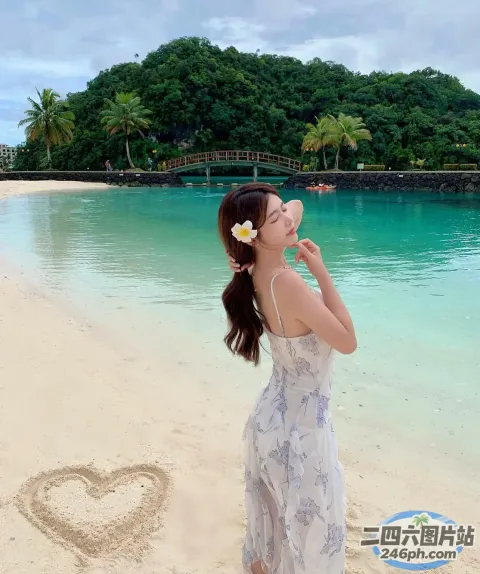 穿着连衣裙的女人站在海滩上，心被画在沙滩上