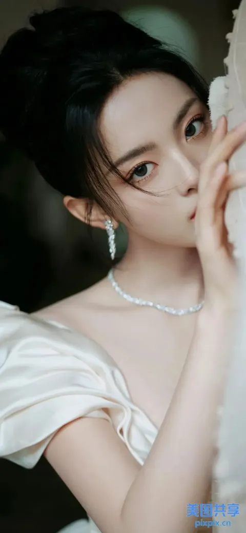 一个身穿白色连衣裙的女人拿着白色窗帘的特写