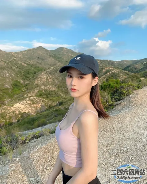 穿着粉红色上衣和黑色短裤的 arafed 女人站在山上