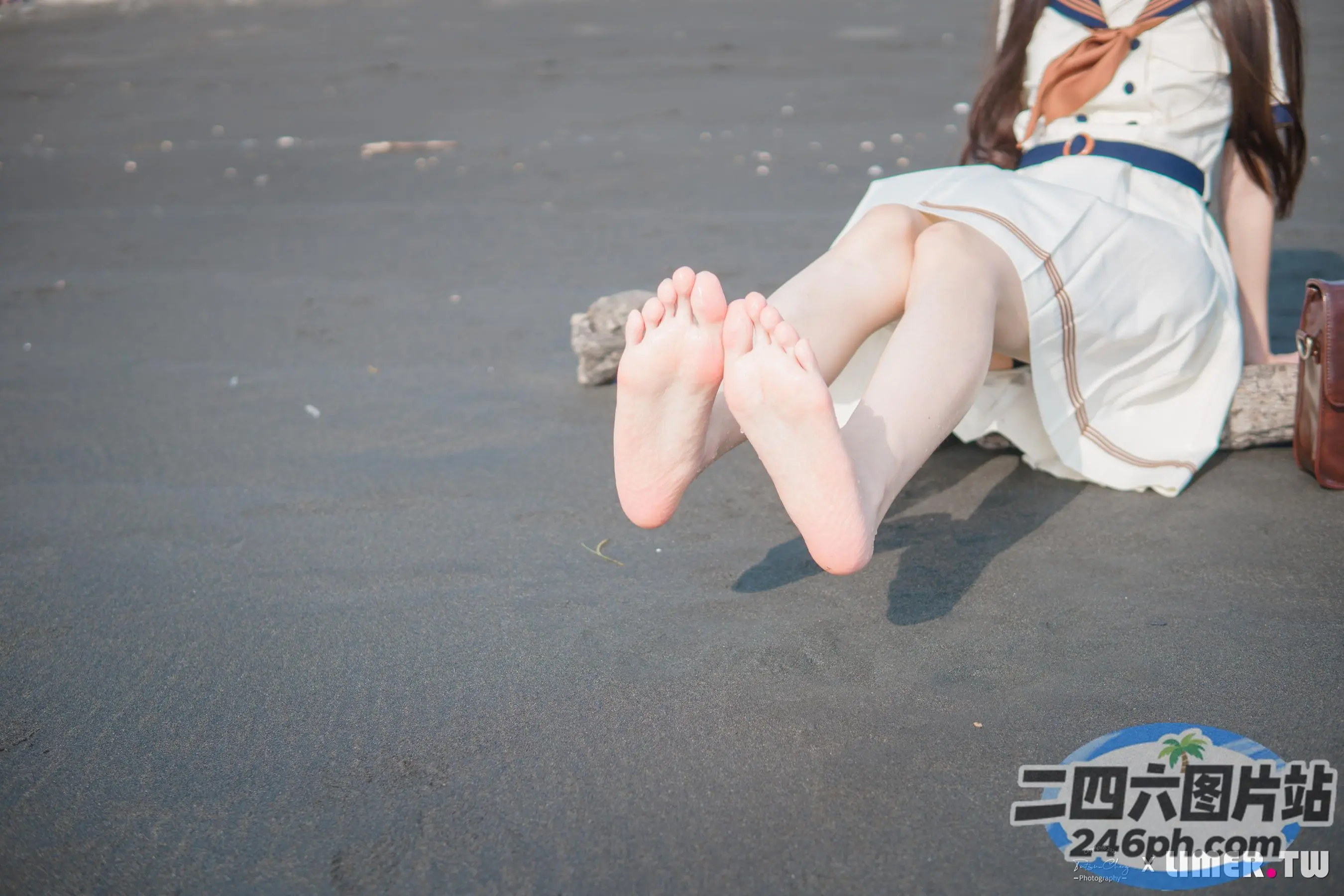 有一个女人坐在海滩上，双脚抬起
