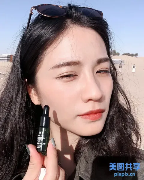 戴墨镜的女人拿着一瓶润唇膏