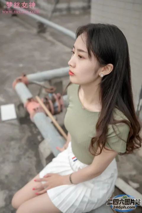 一个女人坐在长凳上，穿着绿色衬衫和白色短裤