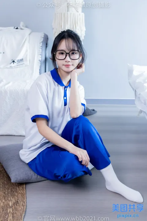 阿拉夫德亚洲妇女坐在床上，穿着白色和蓝色的衬衫
