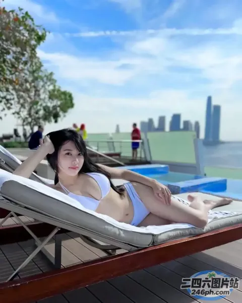 身穿白色比基尼的女人躺在泳池边的躺椅上