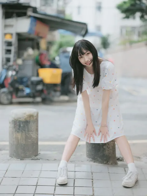 身穿白色连衣裙的 araffe 女孩靠在杆子上