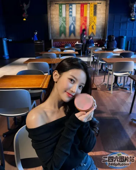 有个女人坐在桌子旁，手里拿着甜甜圈
