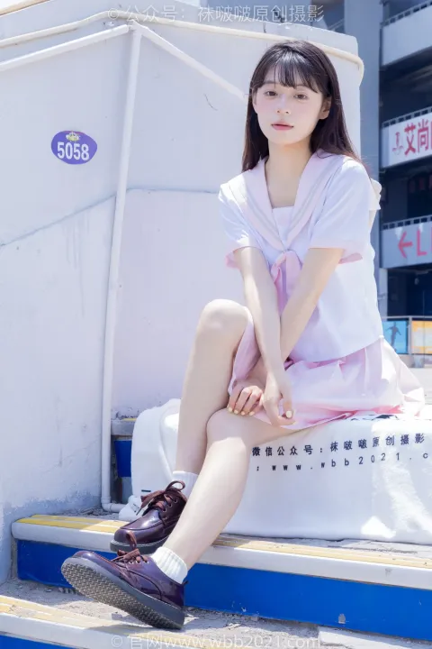 一个女人坐在台阶上，背景是一座白色和蓝色的建筑